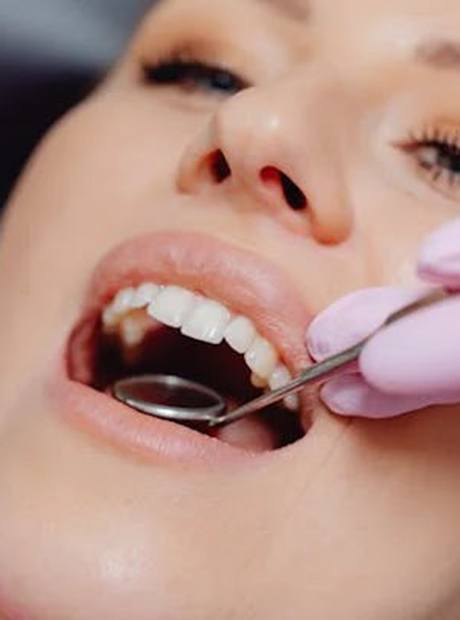 Dentist using dental mirror to look on woman’s mouth